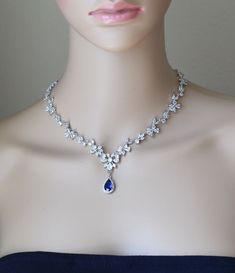 a woman's head wearing a blue dress with a necklace and earrings on it