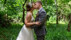 a bride and groom kissing in the woods