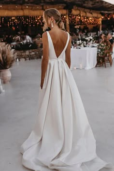 a woman in a white wedding dress looking down at the ground with lights on it