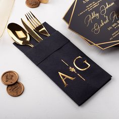 a black napkin with gold foil on it next to some coins and a knife and fork