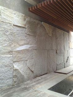 an indoor swimming pool in front of a stone wall