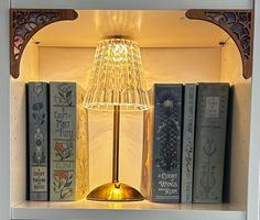 a lamp that is sitting on top of a book shelf next to some other books