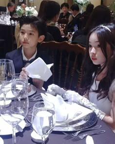 two children sitting at a table with plates and napkins on it in front of them