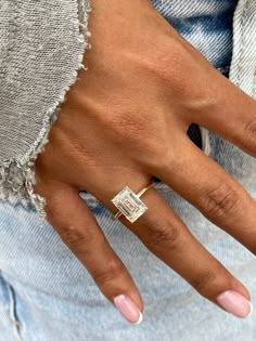 a close up of a person's hand with a ring on their finger and an engagement ring in the other hand