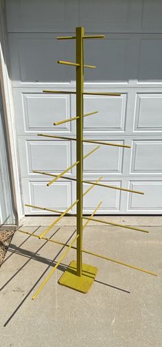 a yellow metal pole with several sticks sticking out of it's sides in front of a garage door