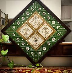 a green and white decorative wall hanging on the side of a wooden window sill