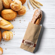 breads and rolls on a white table with a brown paper bag next to them