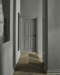 an empty hallway with two doors and wooden floors