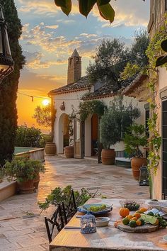 a table with plates of food on it in front of a house at sunset or dawn