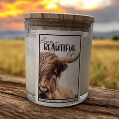 a candle sitting on top of a wooden table in front of a field and sky