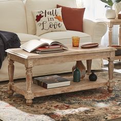 a living room with a couch, coffee table and books on the end tables in front of it