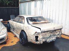 a car that is sitting in the dirt next to another car with it's hood up