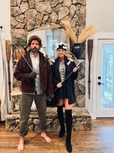 a man and woman dressed up as pirates in front of a stone fireplace with swords