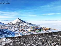 an aerial view of a small town in the middle of snow covered hills and mountains