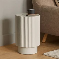 a white vase sitting on top of a wooden floor next to a chair and rug