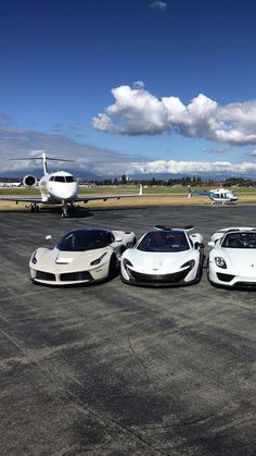 three white sports cars parked in front of an airplane