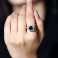 a woman's hand with a ring on it and a blue stone in the middle