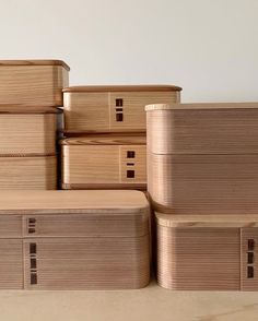 several stacks of wooden boxes stacked on top of each other in front of a white wall