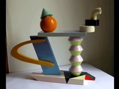 an orange sitting on top of a table next to a stack of different colored objects