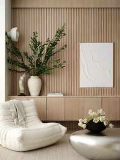 a white chair sitting in front of a vase filled with flowers next to a plant