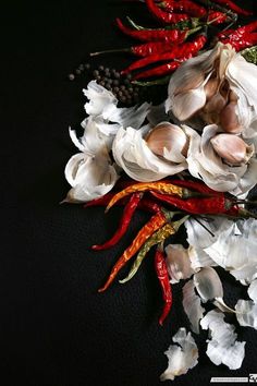 white flowers and red peppers on a black surface