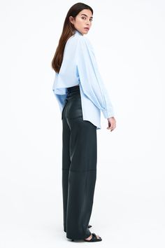 Our Ezra Shirt is a capsule wardrobe dream for your closet. Crafted from 100% crisp European poplin cotton, she offers a classic button-up silhouette in front, but with a cropped back for modern edge. Say hello, as well, to her diagonal seams at the front, sleek collar and long dolman sleeves finished with mother-of-pearl button cuffs. Wear Ezra tucked, tied or open and free—she never fails to inspire new looks.[SPLIT] Rocio, in light blue and in black, is 5'9.5" (175 cm) tall, wearing size XS. Oversized Blouse For Business Casual In Spring, Cropped Shirt For Workwear In Fall, Cropped Workwear Shirt For Fall, Modern Cropped Blouse For Work, Chic Cropped Shirt For Office, Modern Cropped Shirt For Spring, Modern Cropped Shirt For Work, Modern Long Sleeve Cropped Shirt For Work, Relaxed Fit Cropped Blouse For Work