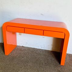 an orange table sitting on top of a carpeted floor