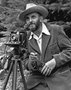 a man in a hat is holding a camera and looking into the distance with a quote on it