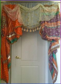 an open door with sheer curtains hanging from it's sides and colorful fabric draped over the top