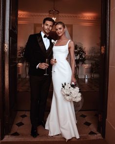 a bride and groom pose for a photo in the doorway to their reception room at an elegant wedding