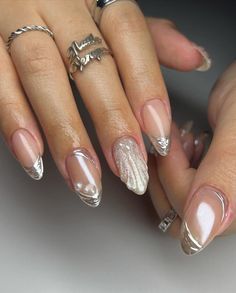 a woman's manicured nails with white and silver designs on them, including rings