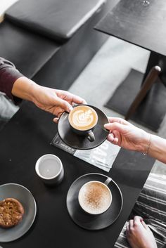 two people sitting at a table with cups of coffee