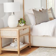 a bedroom with a bed, nightstand and lamp on the side table in front of it