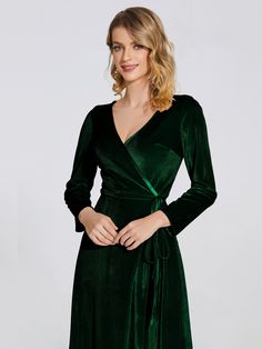 a woman wearing a green velvet dress with long sleeves and a wrap around the waist