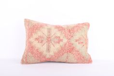 a pink and white pillow with an intricate design on the front, sitting against a white background