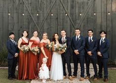 a group of people standing next to each other in front of a wooden wall with lights