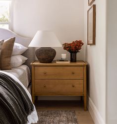 a nightstand with two vases on it next to a bed