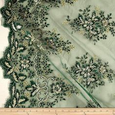 an embroidered fabric with green and white flowers on the side, next to a ruler