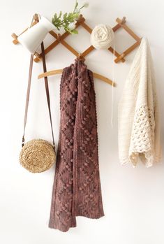 a scarf hanging on a coat rack next to a basket and cup holder with yarn