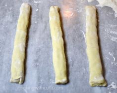 three doughsticks are lined up on a baking sheet and ready to go into the oven