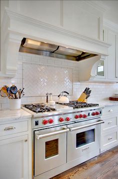 a stove top oven sitting inside of a kitchen next to white cabinets and counter tops