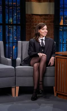 a woman sitting on top of a gray couch next to a man in a black suit