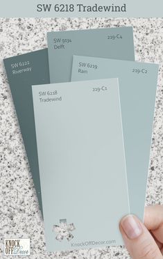 a hand is holding three different shades of paint in front of a white background with the words sw 618 tradewind on it