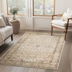 a living room area with white furniture and wooden floors, along with a large rug on the floor