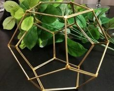 a close up of a metal object on a table with leaves and flowers in the background