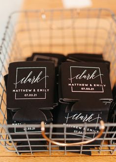 some black and white labels in a metal basket on a wooden table with gold rimmed glasses