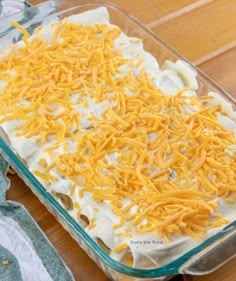 a casserole dish with cheese and sour cream in it on a wooden table