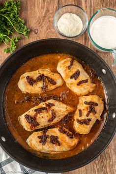 some food is cooking in a skillet on a wooden table next to other ingredients