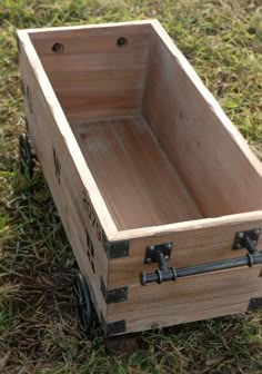 a wooden box sitting in the grass on top of a field with two black handles