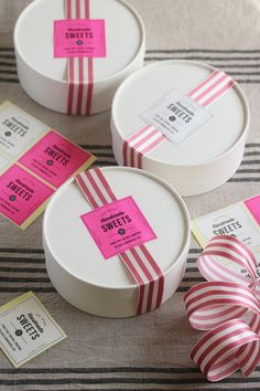 three round boxes with pink and white striped ribbons on the top one has a price tag attached to it